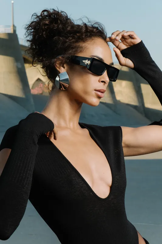 Woman in black sunglasses and a black top wearing silver earrings outdoors, an example of Vidd Studios jewelry work