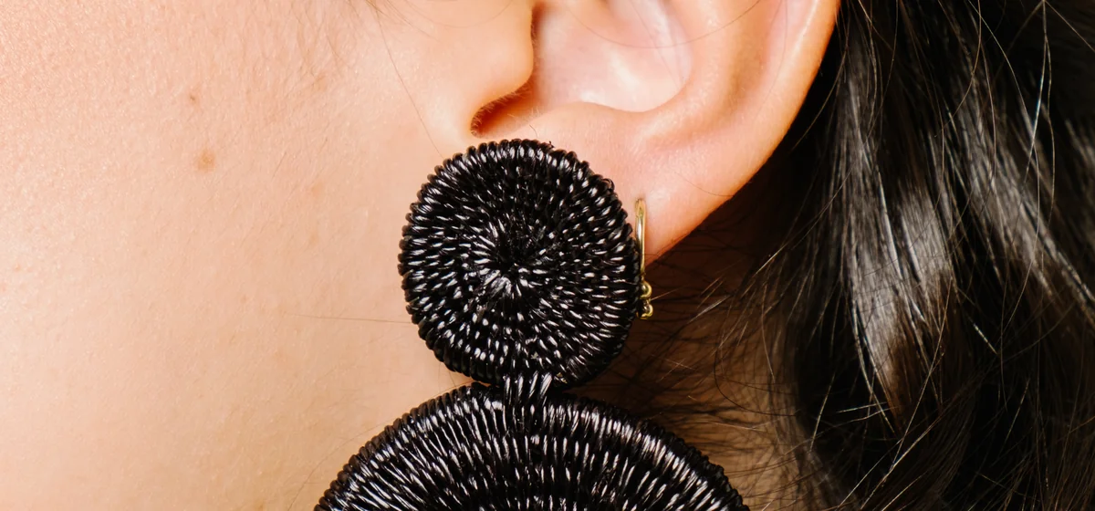 Close-up of a large black woven disc statement earring, an example of Vidd Studios jewelry work