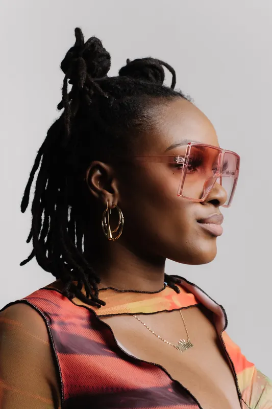 Woman with locs in pink sunglasses wearing gold hoop earrings, an example of Vidd Studios jewelry work